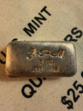 Jackson Precious Metals JPM 5 oz .999 fine silver hand-poured loaf bar with script JPM hallmark, displayed on vintage U.S. Mint quarters bag.